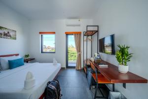 a bedroom with a bed and a desk and a television at Onederz Kampot in Kampot +68 photos