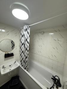 a bathroom with a sink and a tub and a mirror at Modern in Orpington
