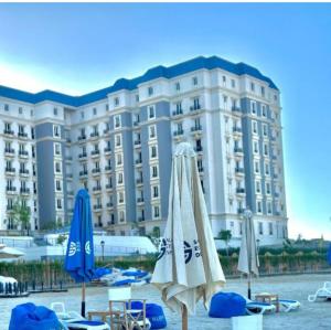 a large hotel with chairs and umbrellas in front of it at Cozy studio in sahel in El Alamein