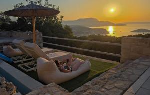 a woman laying in a lounge chair with the sunset in the background at Bliss House Villa in Plaka