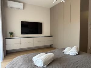 a bedroom with a tv and a bed with towels at MOOD Apartment Piešťany Centrum, parking, terasa in Piešťany