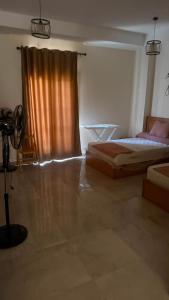 a bedroom with a bed and a window with a curtain at Cozy studio in sahel in El Alamein