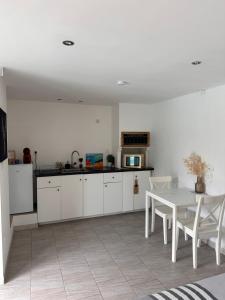 a kitchen with white cabinets and a table with chairs at Dépendance climatisée au sud de Toulouse in Lacroix-Falgarde