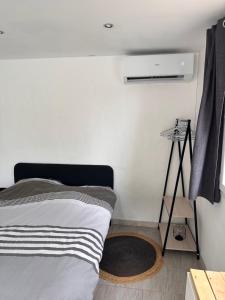 a white bedroom with a bed and a rug at Dépendance climatisée au sud de Toulouse in Lacroix-Falgarde