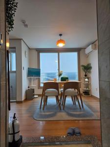 a dining room with a table and chairs and a large window at Aju Good House 아주굿하우스 in Geoje