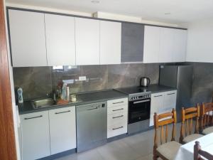 a kitchen with white cabinets and stainless steel appliances at Komarnica Willage home in Šavnik