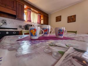 four coffee mugs sitting on a table in a kitchen at Casa con giardino e garage vicino alle piste in San Pietro