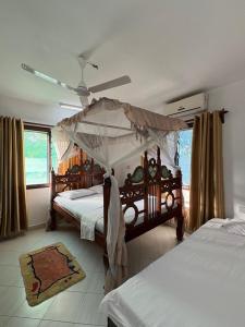 a bedroom with two beds and a canopy bed at Villa Tuffah in Watamu +32 photos