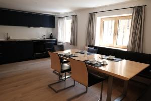 a kitchen and dining room with a wooden table and chairs at Forte Apartments in Klösterle