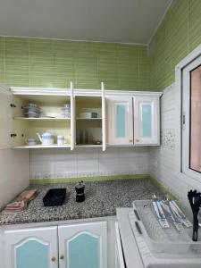 a kitchen with green walls and white cabinets and a sink at Le Minaret in Kairouan +27 photos