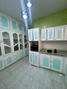 a large kitchen with white cabinets and green walls at Le Minaret in Kairouan