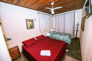 a bedroom with a red bed and a ceiling fan at Pousada Miramar in Marataizes +65 photos