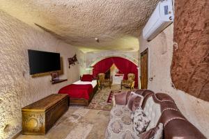 a bedroom with a bed and a tv on a wall at Hidden Cave Hotel in Göreme