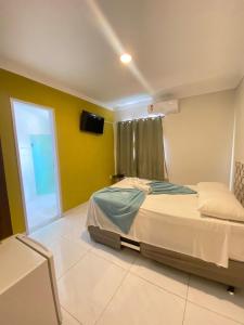 a bedroom with a bed and a tv on the wall at Pousada Inn Blue Horizon in Porto De Galinhas