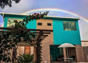 a rainbow in the sky above a blue house at Pousada Inn Blue Horizon in Porto De Galinhas
