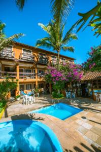 a resort with a swimming pool and palm trees at Pousada Miramar in Marataizes
