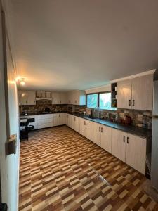 a large kitchen with white cabinets and a wooden floor at Baam-E-Noor , Pine Tree Resort , Margalla Hills Islamabad in Harīpur
