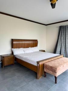 a bedroom with a wooden bed and a bench at Baam-E-Noor , Pine Tree Resort , Margalla Hills Islamabad in Harīpur