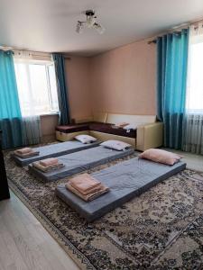 three beds in a room with blue curtains and a rug at SunLake House in Balykchy