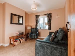 a living room with a blue couch and a chair at Copper Beech Cottage in Welshpool