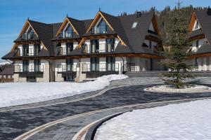 a large house in the snow with a driveway at Residence Tatrzański Park in Poronin