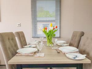 a dining room table with plates and flowers in a vase at Ben Vorlich Lodge in Saint Fillans
