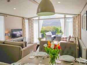 a living room with a table with flowers on it at Ben Vorlich Lodge in Saint Fillans +22 photos