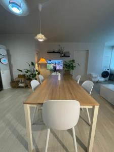 a dining table with white chairs in a living room at Busan Harbor Stay in Busan