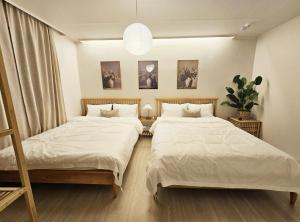 a bedroom with two beds and a potted plant at Busan Harbor Stay in Busan