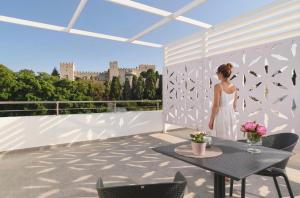 a woman in a white dress standing on a balcony at Castelo View Luxury apt in Rhodes Town