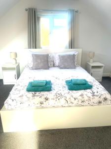 a large white bed with two green pillows on it at Spacious airy modern private detached house in Beeston