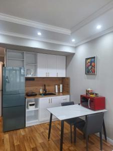 a kitchen with white cabinets and a table with a microwave at Undraa's cosy small apt in Ulaanbaatar +4 photos