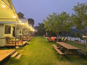 a row of picnic tables and chairs next to a building at מאי טאי ויליג' - 8 בקתות מהממות מול הנוף in Mas'ada