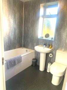 a bathroom with a sink and a tub and a toilet at Spacious airy modern private detached house in Beeston +41 photos