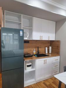 a kitchen with white cabinets and a black refrigerator at Undraa's cosy small apt in Ulaanbaatar