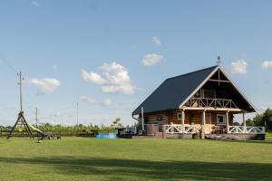 a large log cabin with a playground in a field at Vējkalni in Myza Dzirtsiyems