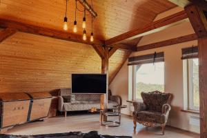 a living room with wooden ceilings and a flat screen tv at Vējkalni in Myza Dzirtsiyems