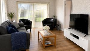 a living room with a couch and a tv at Coed Bach Suite in Bryngwran
