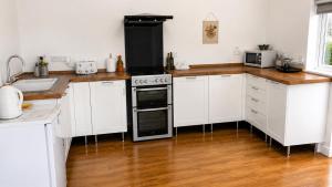 a kitchen with white cabinets and a stove at Coed Bach Suite in Bryngwran