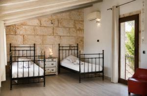 two beds in a room with a stone wall at Cas Coco – 8-Person Townhouse near Playa de Muro ⭐ in Muro +19 photos