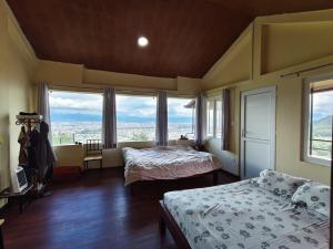 a bedroom with two beds and large windows at Penance Homestay in Khokna