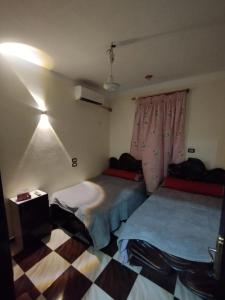 a room with two beds in a room with a checkered floor at Couple's Cove in Luxor