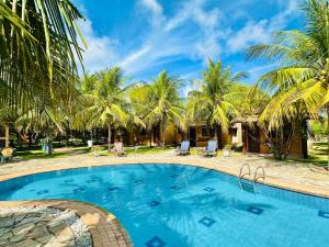 a swimming pool in a resort with palm trees at Hotel Enseada Maracajaú in Maracajaú