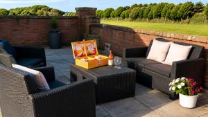 a patio with two wicker chairs and a table at Coed Bach Suite in Bryngwran