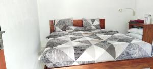 a bed with a black and white comforter and pillows at Live lombok homestay in Batukliang
