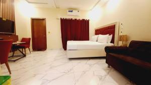 a hotel room with a bed and a desk and a couch at Dove INN Express II in Lahore
