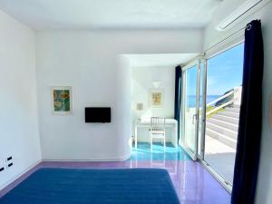 a white room with a blue carpet and a balcony at La Dimora sul Mare in Sant'Angelo D'Ischia