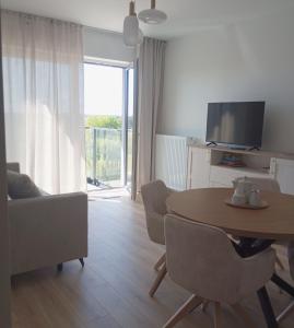 a living room with a table and chairs and a television at Kawalerka pod lasem in Poddębice