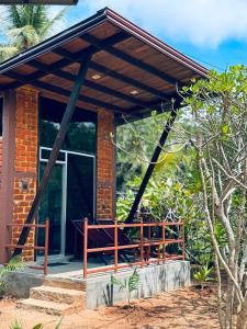 a brick house with awning and a porch at Glass Roof Southern Edge Cabanas in Tangalle