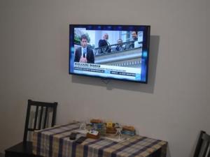una televisione appesa a un muro sopra un tavolo con un tavolo di Ines Downtown B&B a Roma
